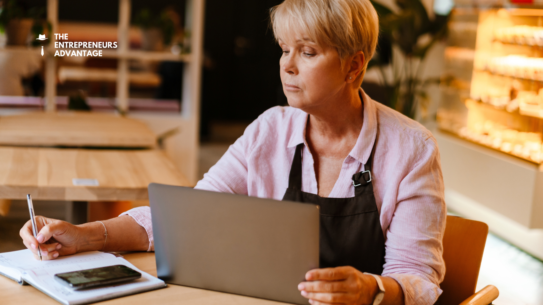 mature-woman-cafe-laptop-business-growth-tools A mature white woman sits at a cafe table using her laptop to implement DIY business growth tools.